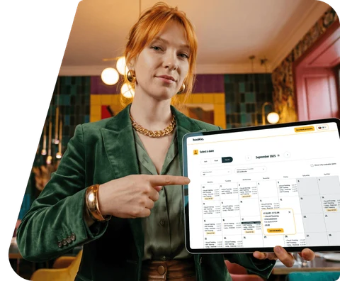 A salon owner pointing at the Bookio booking calendar on a tablet